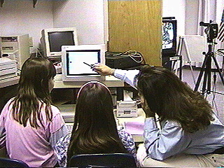 Teacher and students collaborating on a computer project.