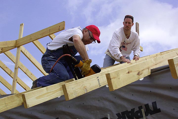Two volunteers work on the roof of a Habitat for Humanity house.