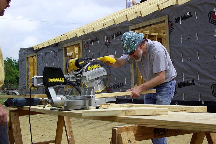 A volunteer prepares to cut a two by four board for use in the house.