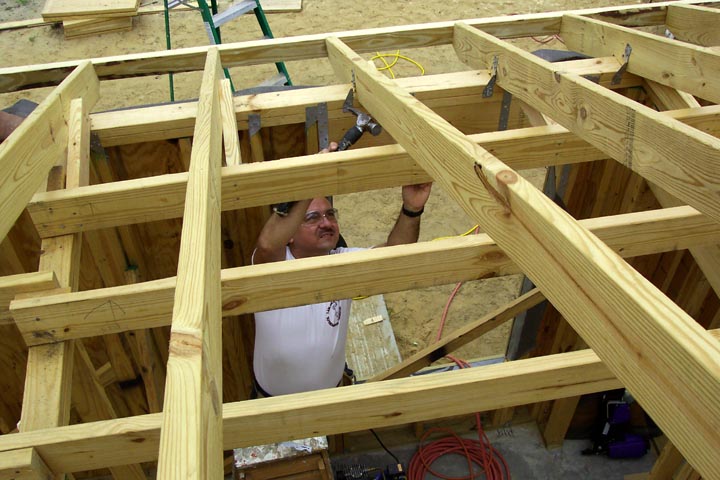 A volunteer works on the roof support of a Habitat for Humanity house.