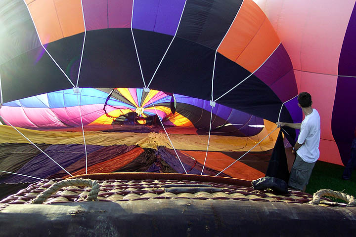 A young man hold the opening of the balloon open in prepartions for liftoff.