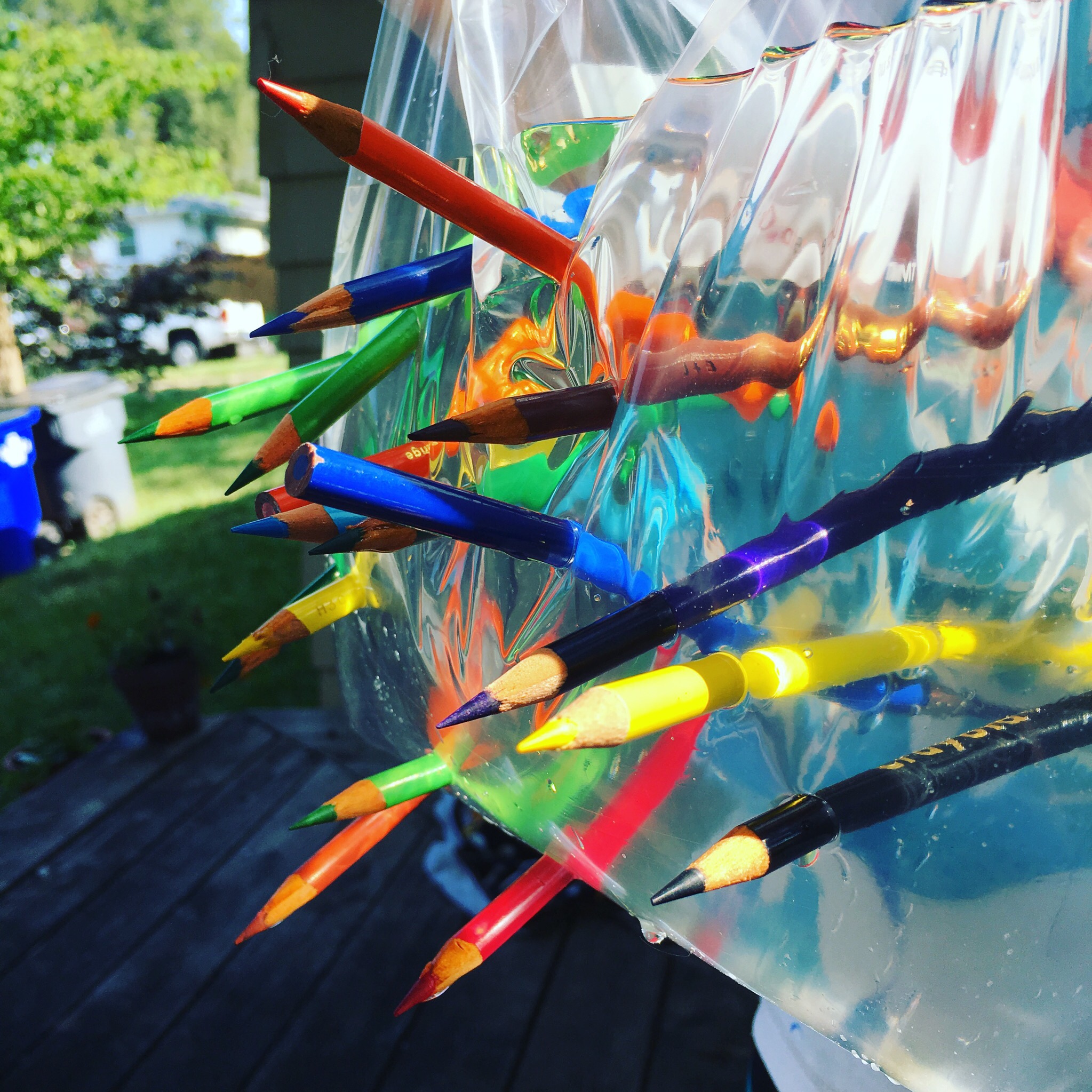 Colored pencils passing through water inside plastic bag