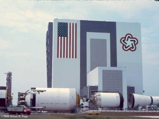 The Vehicle Assembly building at the Kennedy Space Center with a Saturn V in the foreground.