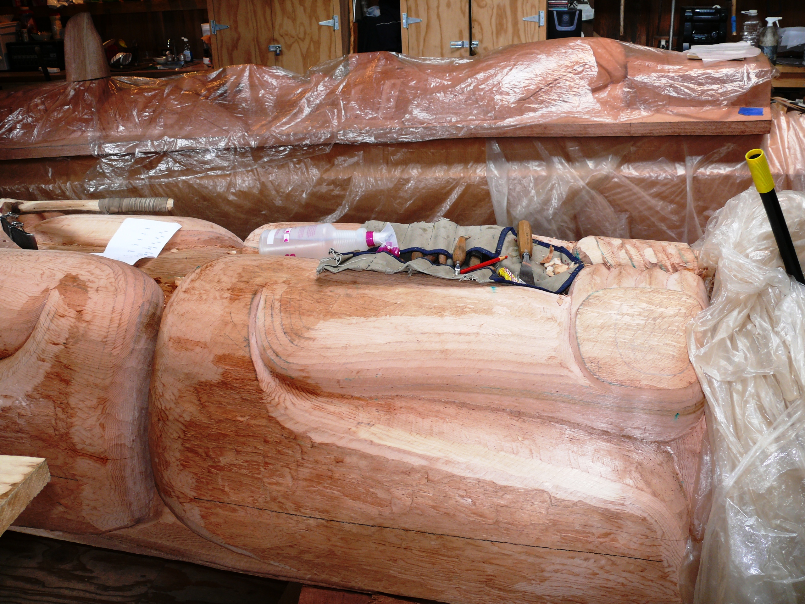 Woodworking tools sit at the ready on a current totem pole carving.