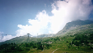 View of cable car at Diavolizza - cows one side of mountains and hikers ready to go up