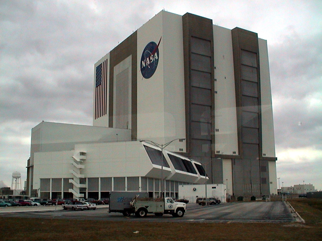 Vertical Assembly Building and Launch Control (smaller building in front) for the Space Shuttle. The VAB building is so large that the width of a school bus is about the same size as one of the strips on the flag.